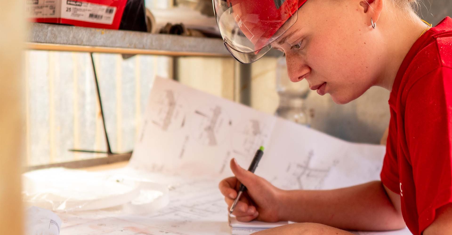 Das Bild zeigt eine junge Frau beim Planlesen. Es symbolisiert, dass das Baumeister Kurszentrum Effretikon BKE massgeschneiderte, auf die Bedürfnisse einer Bauunternehmung zugeschnittene Weiterbildungen anbietet. Diese werden im BKE oder vor Ort in der Bauunternehmung durchgeführt.